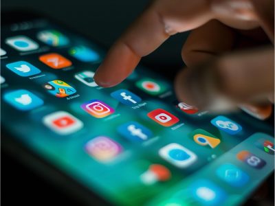 User tapping social media apps on a smartphone, illustrating platforms involved in addressing social media self harm